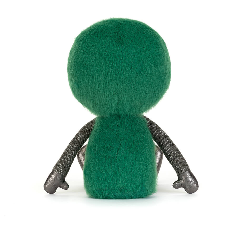 Back view of a soft toy of a green alien with large black eyes against a white background.