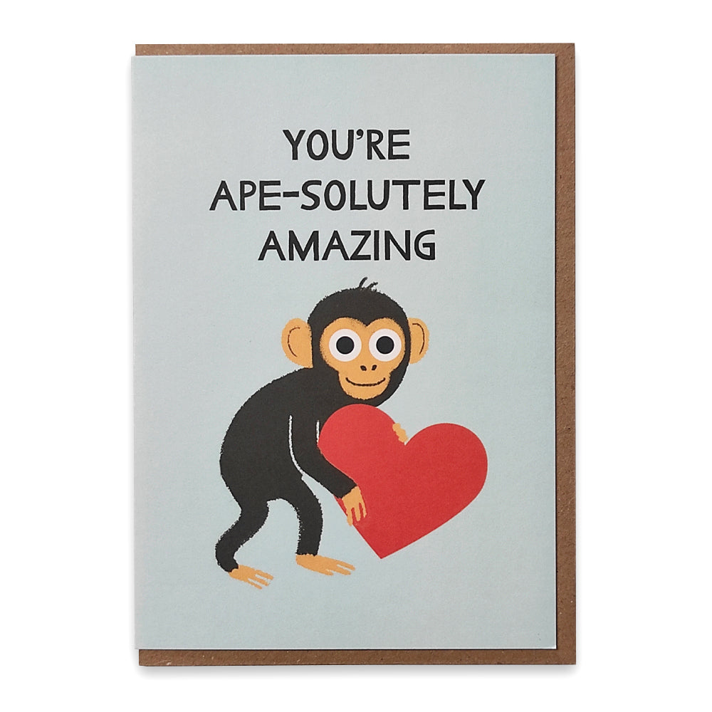 A photograph of a greetings card with an illustration of a chimpanzee holding a red love heart with the words" You're ape-solutely amazing" above.