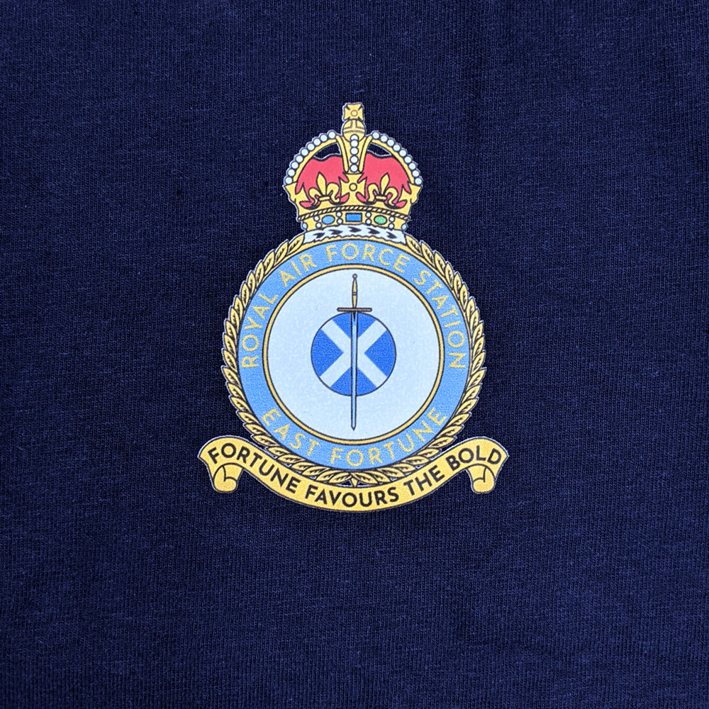 Detail of the east fortune Royal Air Force badge printed on a navy blue tshirt. A sword lays over a Saltire flag which sits in the centre of a round crest topped by a royal crown.