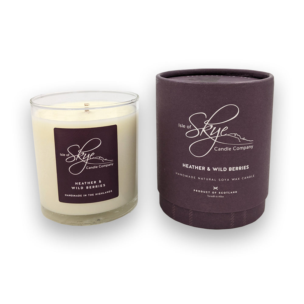 A candle in a glass holder to the left of a round purple box against a plain white background.