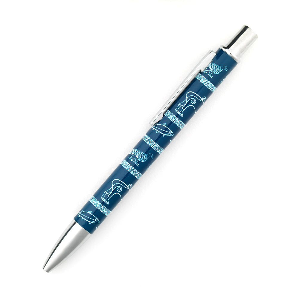 A metal retractable ball point pen with a repeating pattern taken from Pictish carvings of an eagle, a boar, a lion, a fish, and a goose on a blue background. the pen cap, clicker and clip are silver.