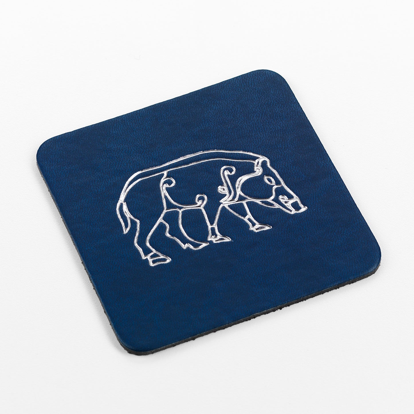 A square blue leather coaster embossed with detailing of a boar taken from Pictish carvings.