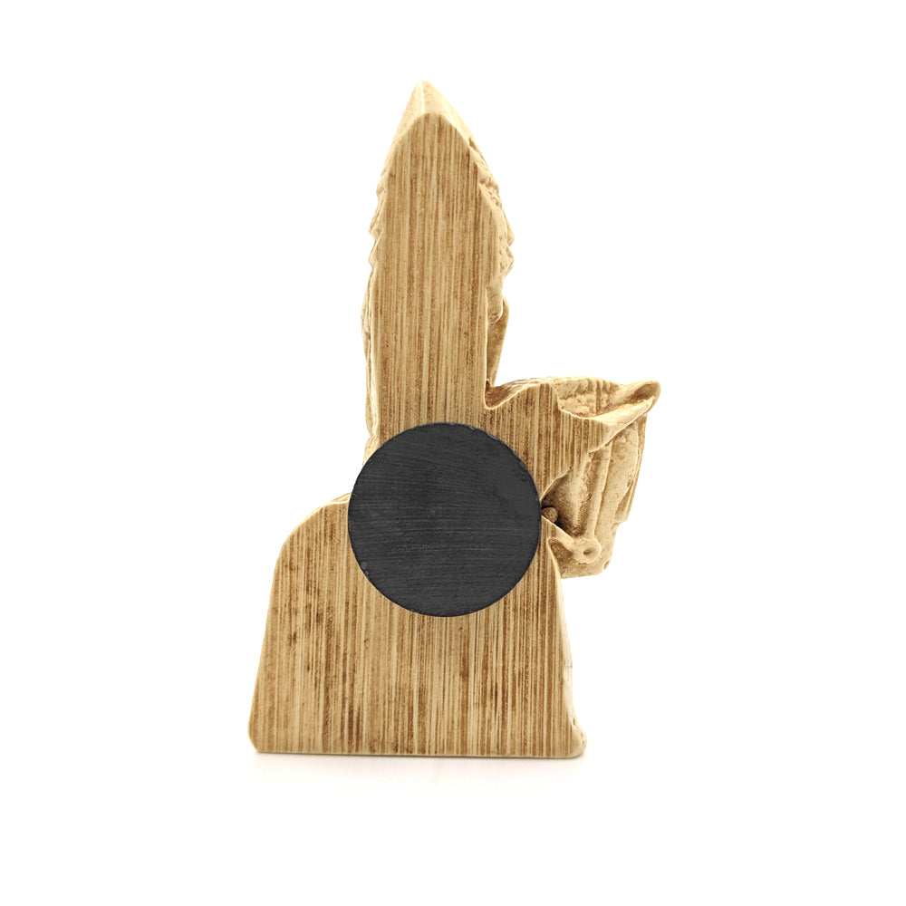 A plastic resin replica magnet of a knight Lewis chess piece. A side view with the knight cut in half with a round magnet attached to the back.
