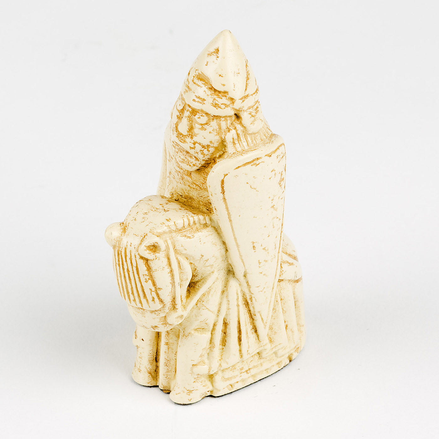 A resin replica of a knight Lewis chess piece. The knight is wearing a pointed helmet and is riding a horse. In his right hand he is holding a spear and a shield in his left hand.