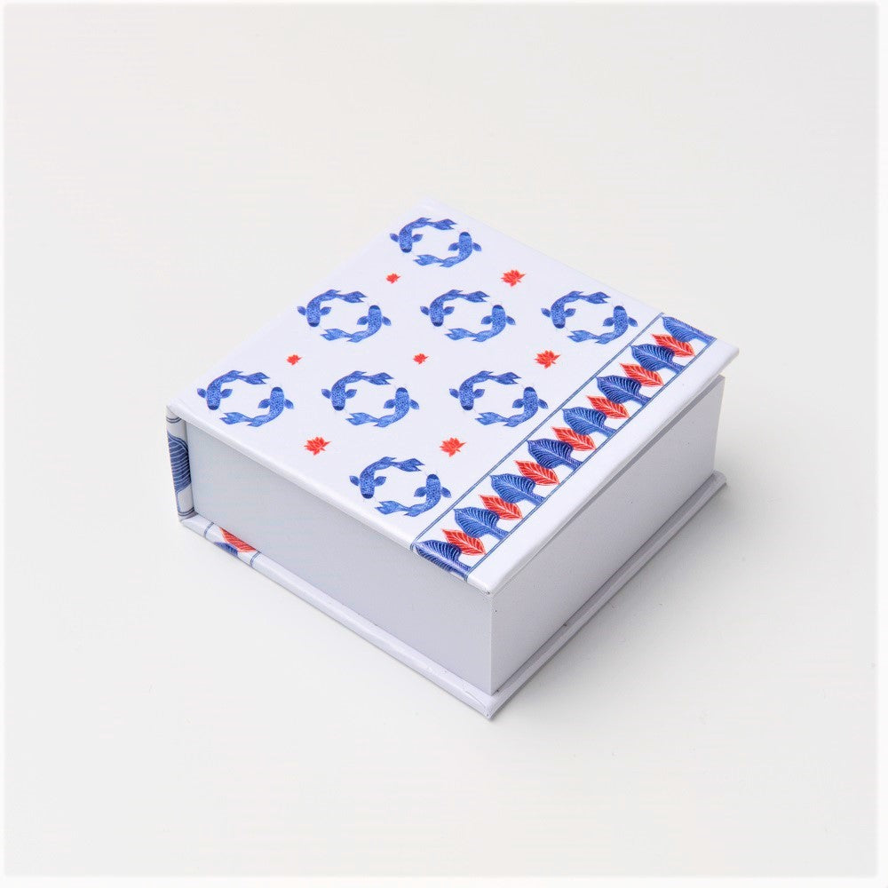 A square pad of white sticky notes with a repeating pattern of blue circling fish and red lotus leaves against a white background in the style of Ming china.