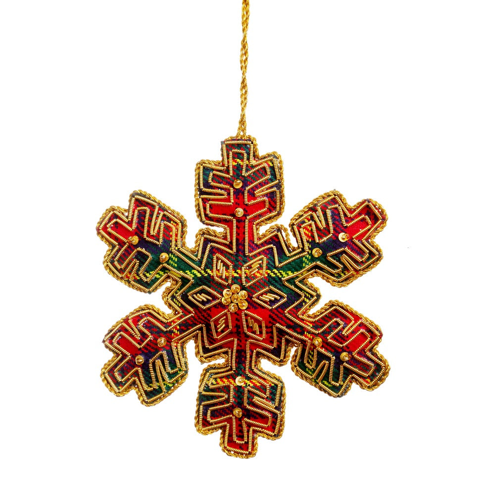An embroidered hanging decoration of a snowflake. The decoration is made from a red and green tartan and embroidered with gold thread and sequins.