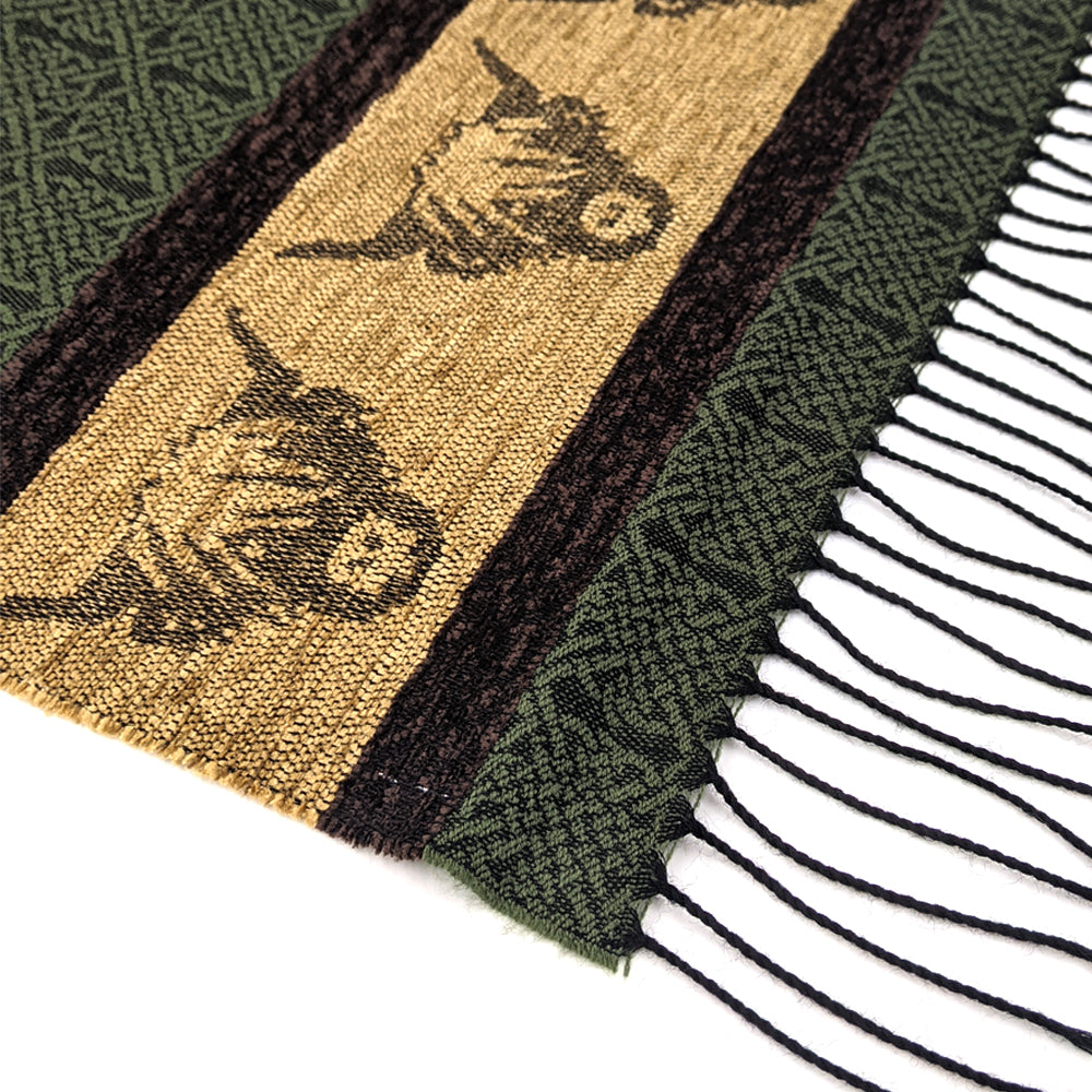 Dark green tassled scarf detail with a celtic roundal and highland cow pattern against a plain white background.