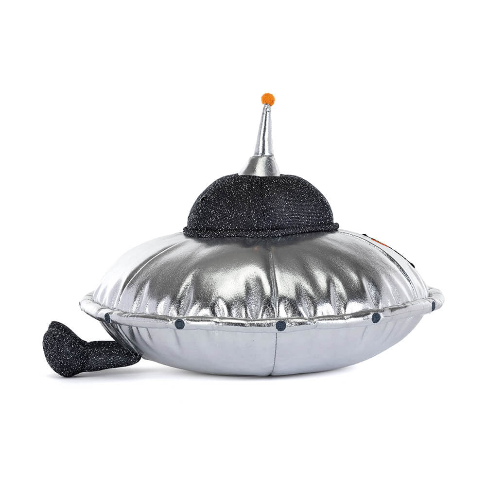 A side view of a soft toy of a shiny silver flying saucer with legs and a smiley face against a plain white background.