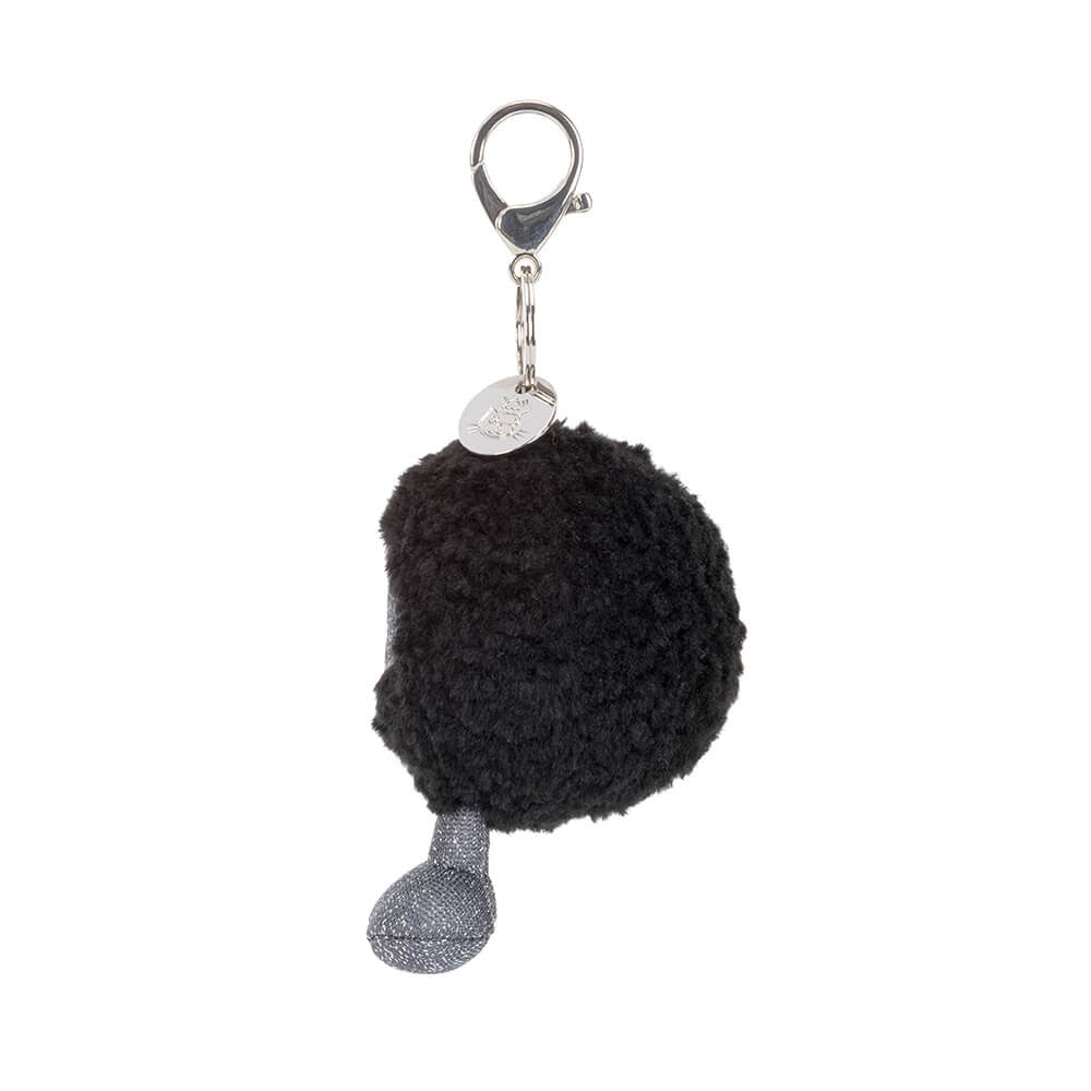A side view of a black round plush keychain with a smiling face and grey legs on a white background