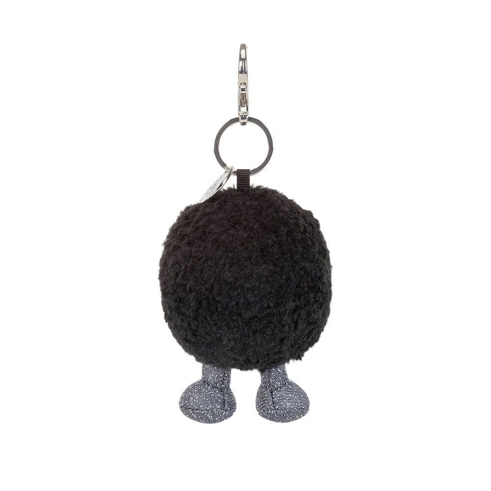 A back view of a black round plush keychain with a smiling face and grey legs on a white background