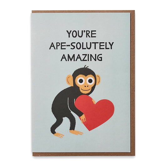 A photograph of a greetings card with an illustration of a chimpanzee holding a red love heart with the words" You're ape-solutely amazing" above.