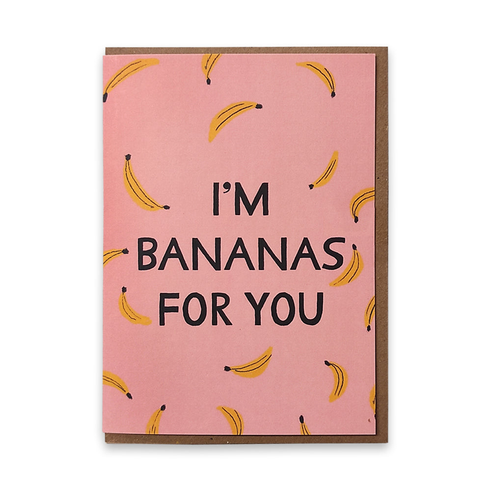 A photograph of a greetings card with a repeating illustrated banana pattern against a pink background with the words "I'm bananas for you" in the middle.