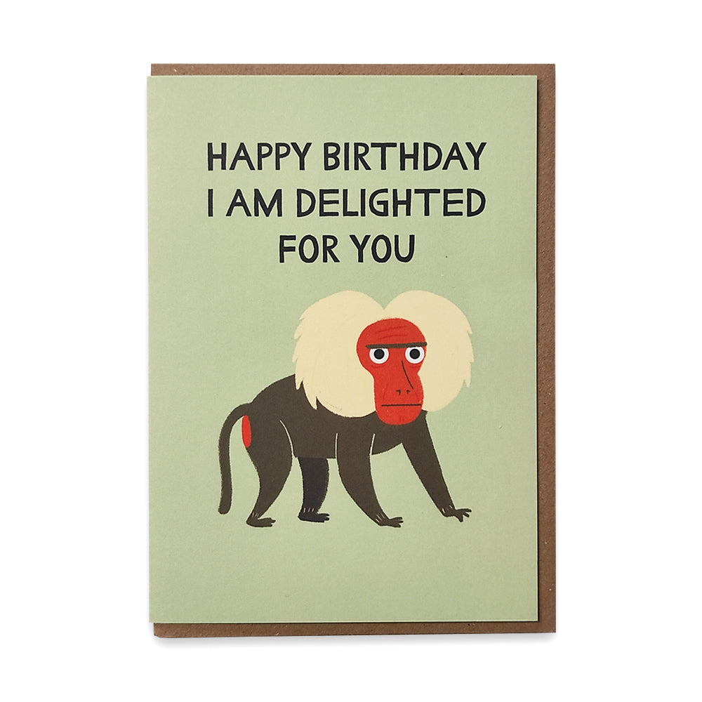 A photograph of a greetings card with an illustration of a grumpy baboon against a pale green background with the words "happy birthday I am delighted for you" above it.
