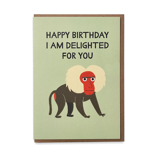 A photograph of a greetings card with an illustration of a grumpy baboon against a pale green background with the words "happy birthday I am delighted for you" above it.