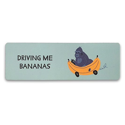 A paper bookmark with an illustration of a gorilla driving a car shaped like a banana with the words "driving me bananas" to the left of it.