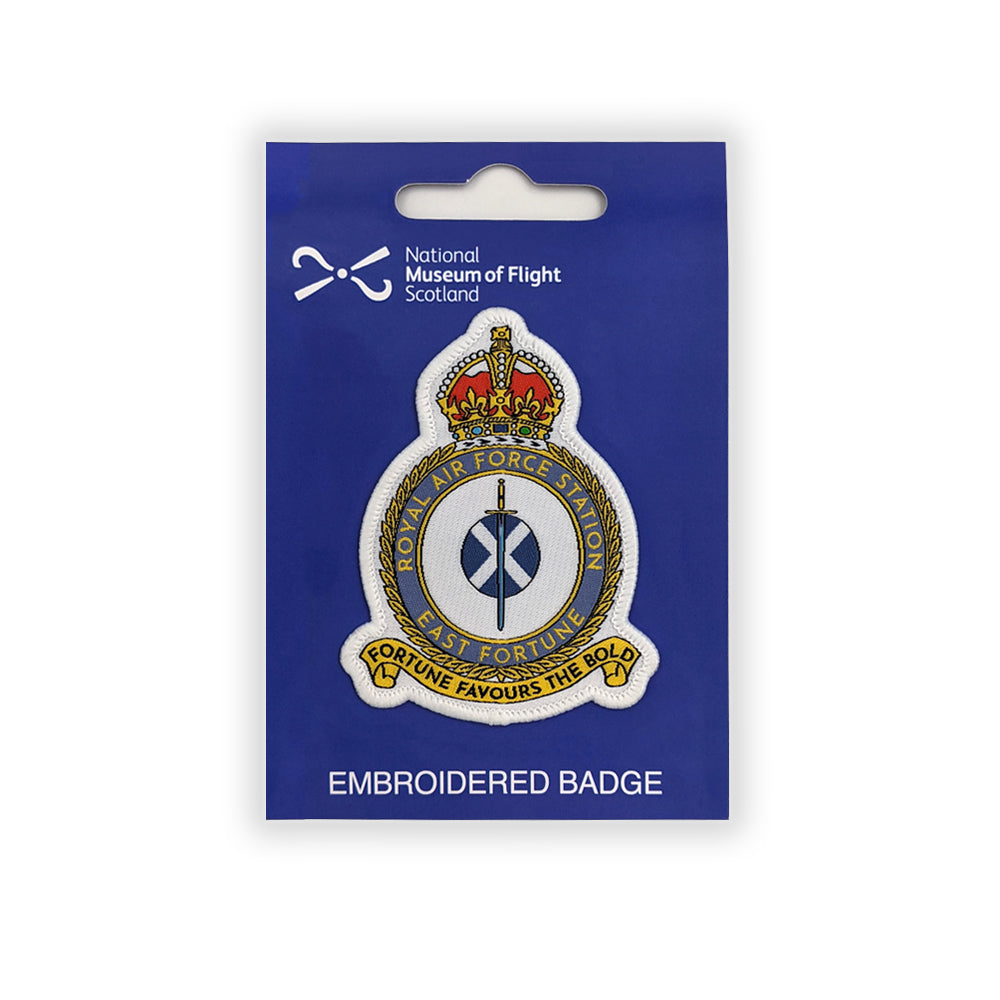 An embroidered patch of the East Fortune Royal Air Force badge. A sword lays over a Saltire flag which sits in the centre of a round crest topped by a royal crown.