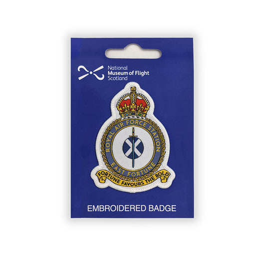 An embroidered patch of the East Fortune Royal Air Force badge. A sword lays over a Saltire flag which sits in the centre of a round crest topped by a royal crown.