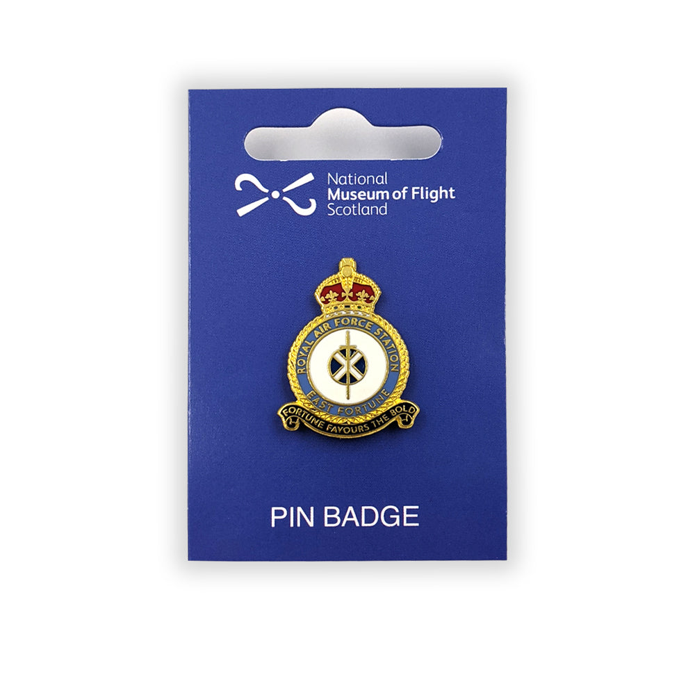 An enamel pin badge against a blue backing card of the east fortune Royal Air Force badge. A sword lays over a Saltire flag which sits in the centre of a round crest topped by a royal crown.