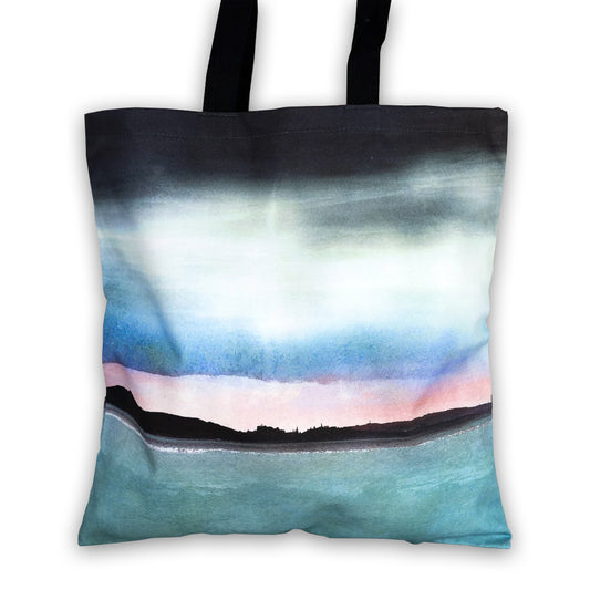 Tote bag with a watercolour painting of Edinburgh's skyline silhouetted over a pink sunset.