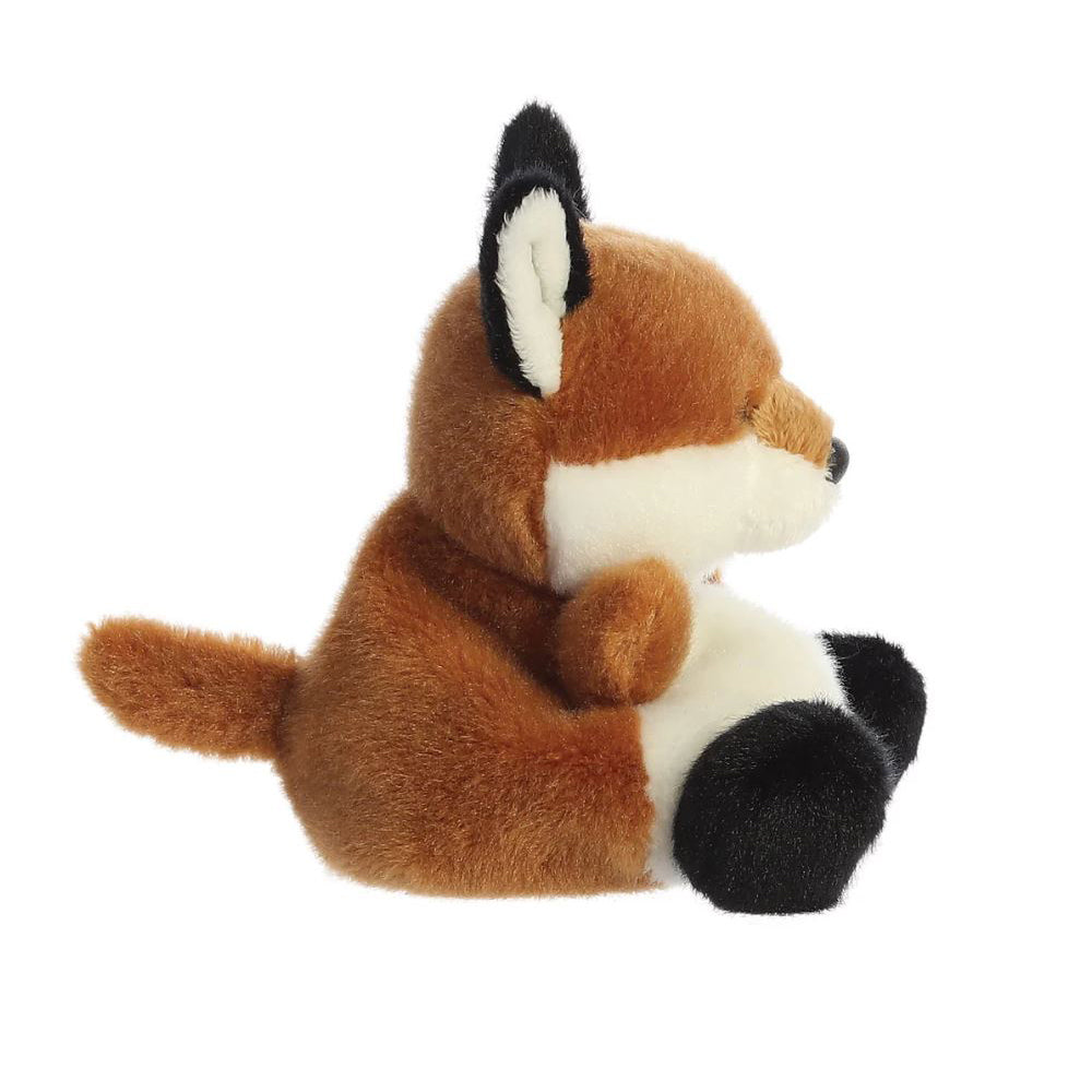 A side view of a small orange and white soft toy fox with black beaded eyes sitting against a plain white background.