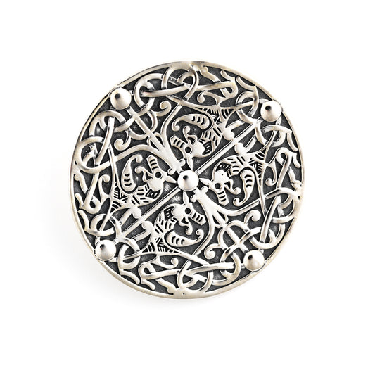 A round silver brooch, with a four way symmetrical design of four beasts,intertwined with vegetation, against a plain white background