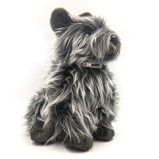 A soft toy of a Skye terrier wearing a collar with the name "Bobby" embroidered on it. 