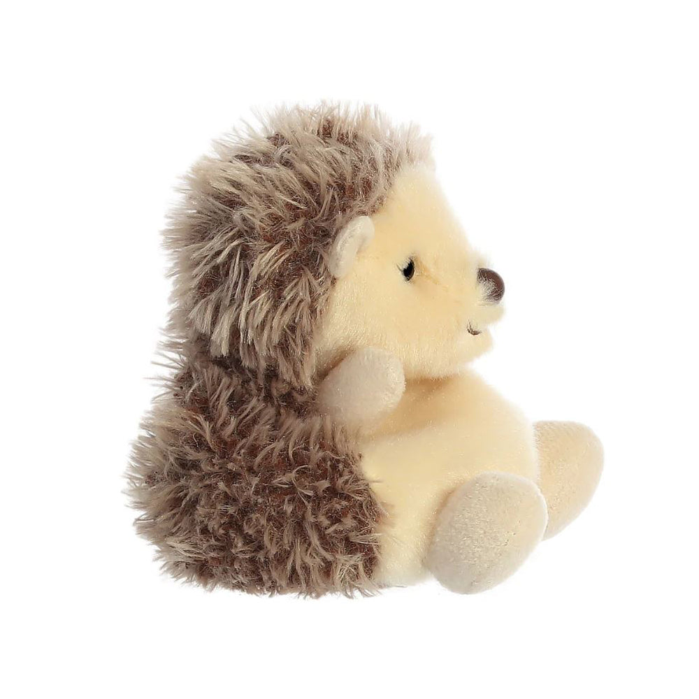 A side view of a small brown hedgehog soft toy with black beaded eyes and a brown plastic nose sitting against a plain white background.