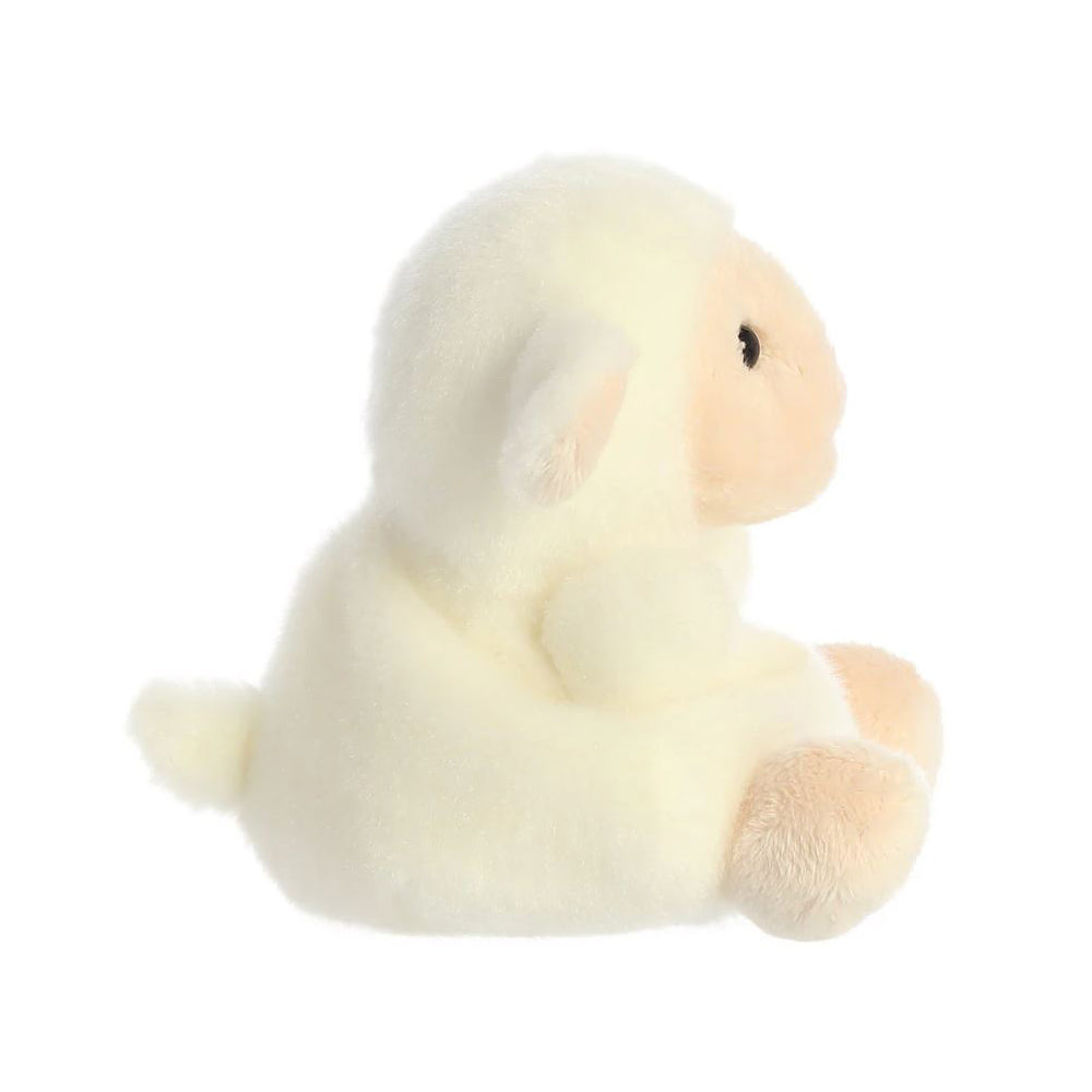 A side view of a small white and pink lamb soft toy with black bead eyes sitting against a plain white background.