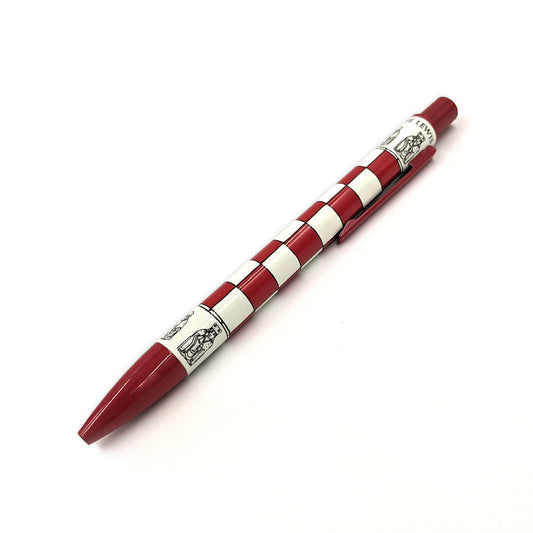 A red retractable ballpoint pen with a chess board pattern around the middle. Above and below the chessboard are line illustrations of the Lewis Chess pieces, the words "The Lewis Chessmen" circles the top edge of the body of the pen.