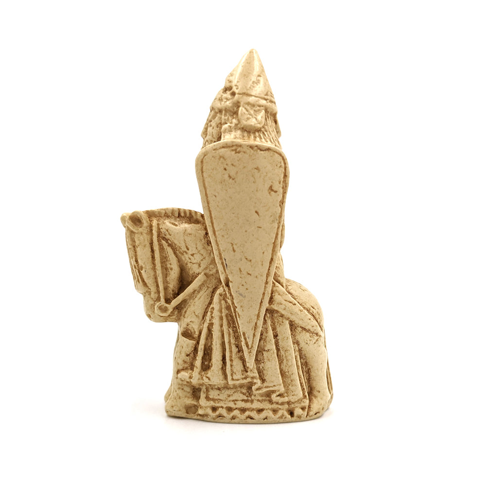 A plastic resin replica magnet of a knight Lewis chess piece. A knight on a horse facing left, the knight is wearing a pointed hat and holding a large body length shield.