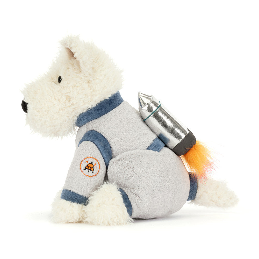 Side view of a plush white Scottie dog in a grey space suit with a shiny silver jetpack with fluffy orange flames against a white background.