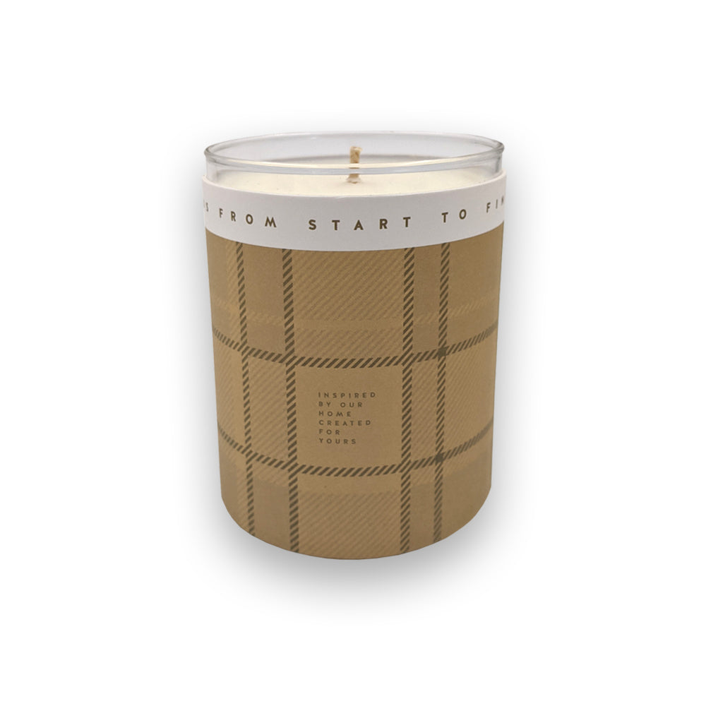 A candle in a glass holder and beige casing against a plain white background.