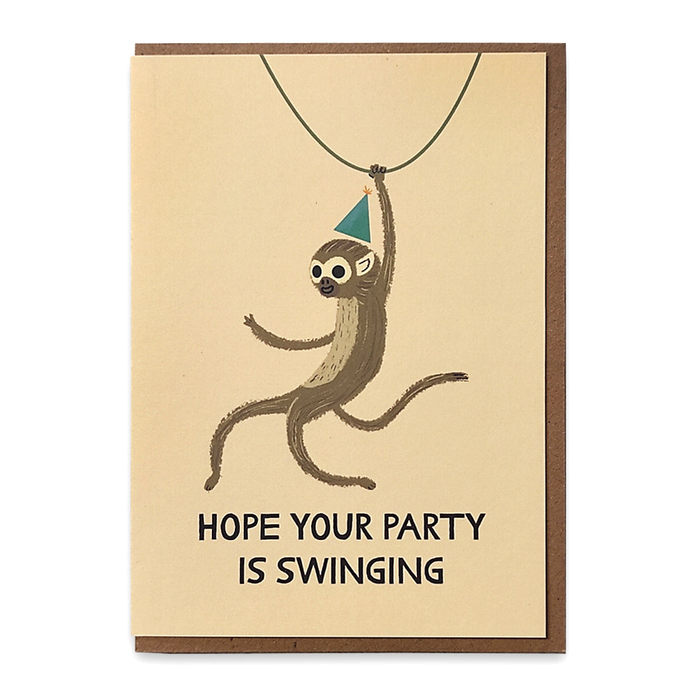A photograph of a greetings card with an illustration of a monkey wearing a party hat swinging form a vine with the words "Hope your party is swinging" underneath.