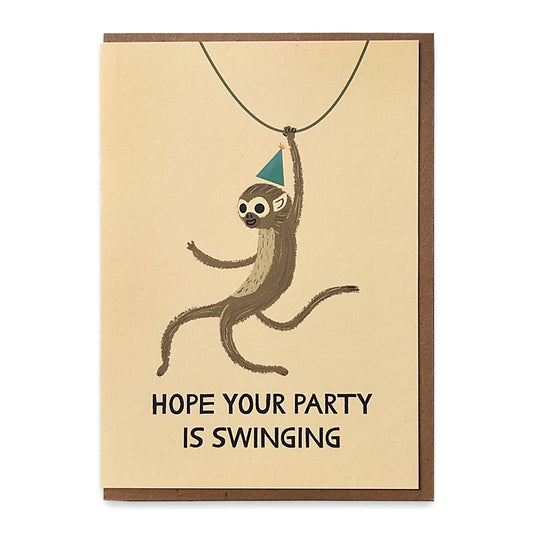 A photograph of a greetings card with an illustration of a monkey wearing a party hat swinging form a vine with the words "Hope your party is swinging" underneath.