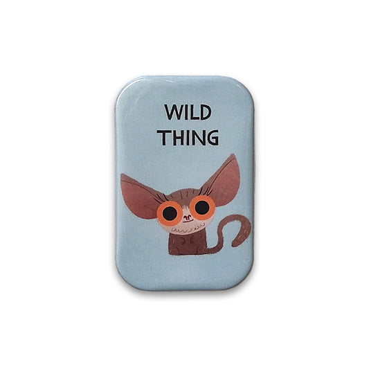 A photograph of a pale blue rectangular magnet with rounded corners against a plain white background. The magnet is printed with an illustration of a bush baby with large orange eyes, above it are the words "wild thing".