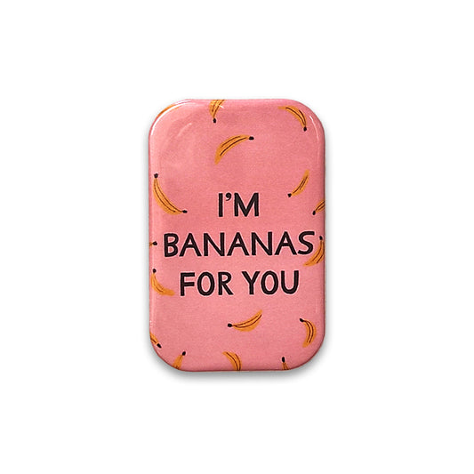 A photograph of a pink rectangular magnet with rounded corners against a plain white background. The magnet is printed with an illustrated pattern of bananas and the words "I'm bananas for you".