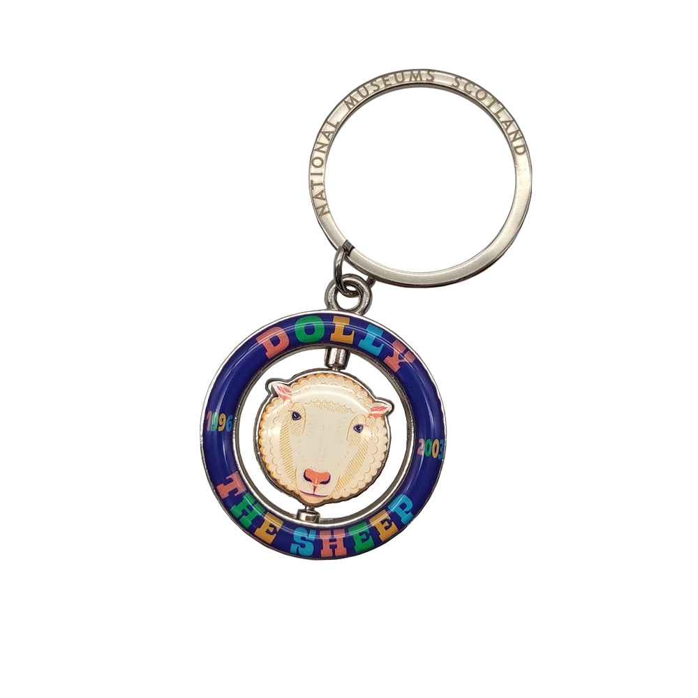 A blue ring keyring with the words 'Dolly the sheep' in various colours round it. In the centre of the ring is a spinning Dolly the sheep's face.