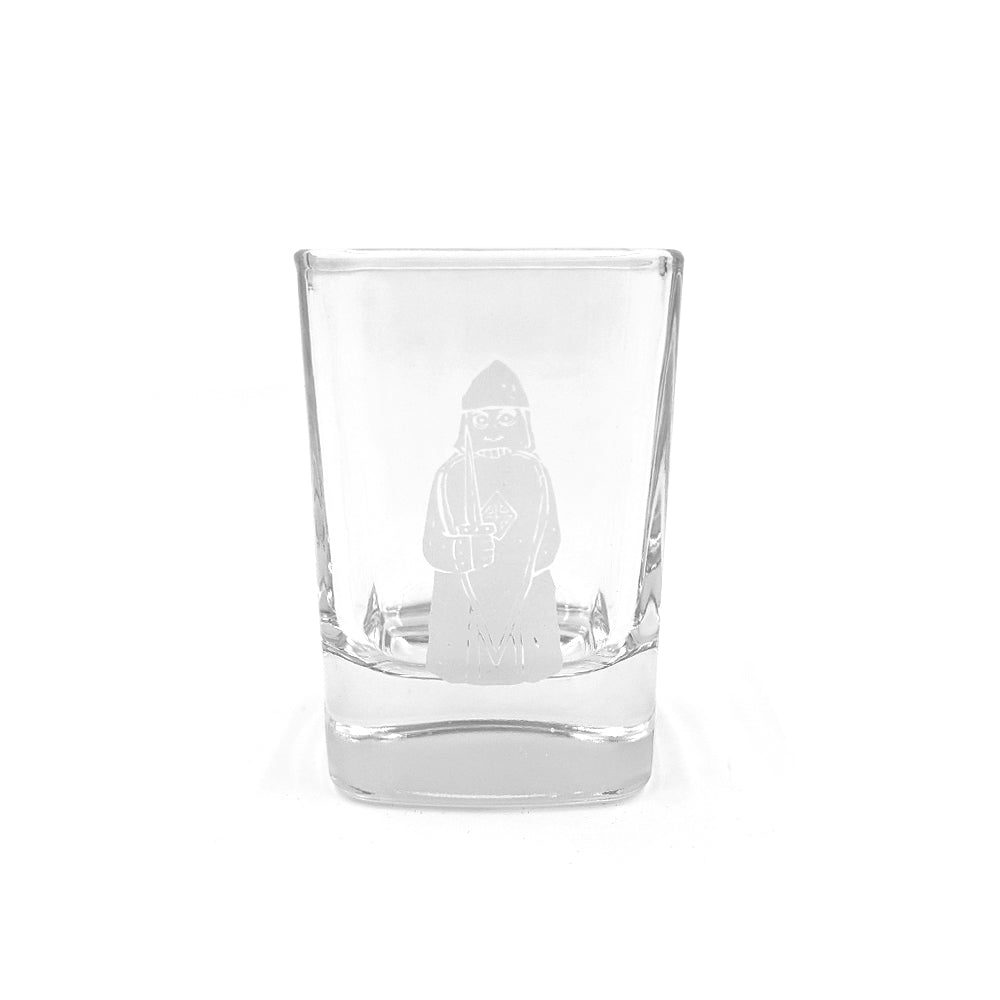 A rounded square shot glass with a printed illustration of a berserker Lewis chess piece in grey.