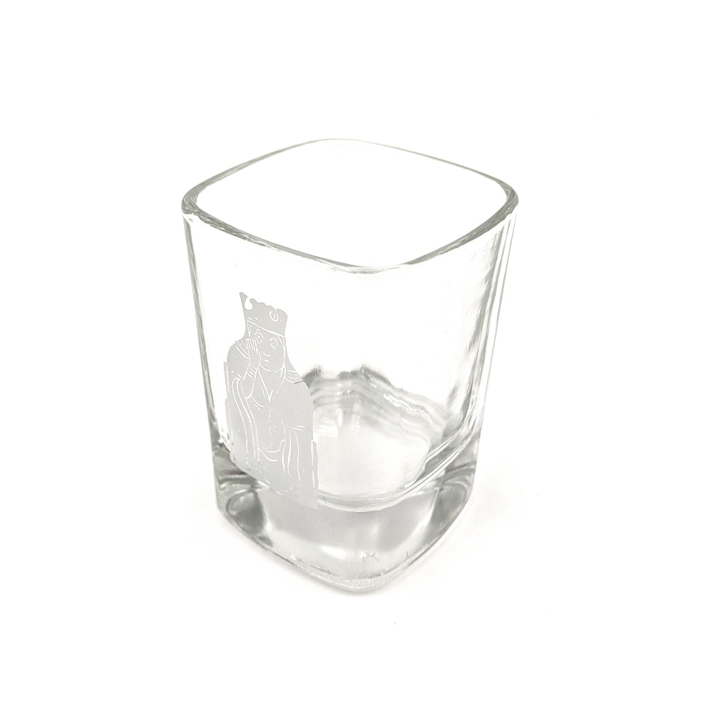 A rounded square shot glass with a printed illustration of a queen Lewis chess piece in grey.