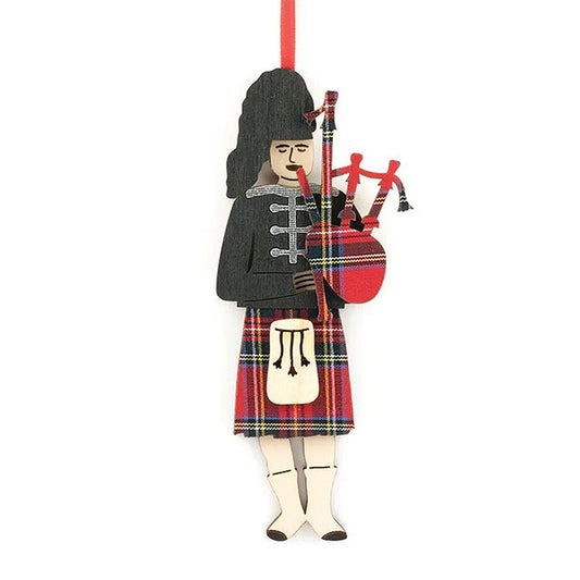 A wooden cut out decoration of a bagpiper wearing a kilt. The decoration is decorated with a red tartan pattern.