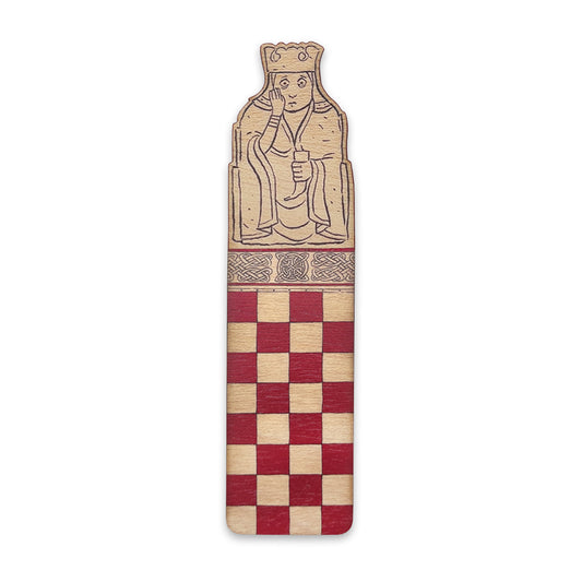 A wooden bookmark with the top half illustrated with a queen Lewis chess piece and the bottom half with a red chessboard style grid.