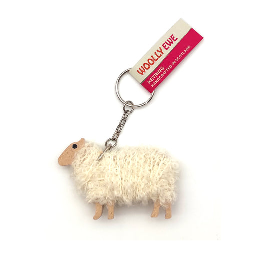 A keyring of a sheep made of wood and white wool against a plain white background