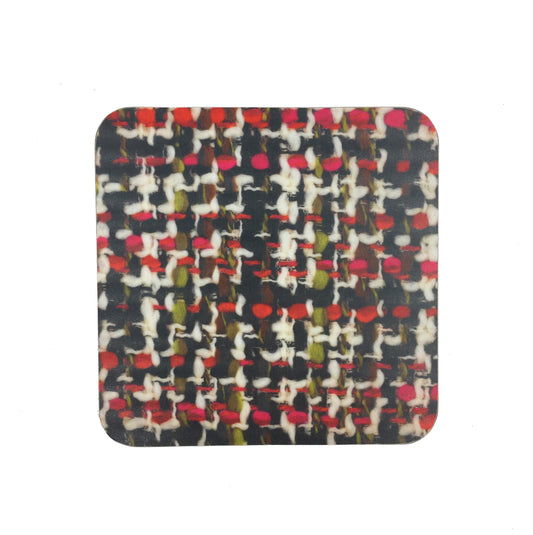 A square coaster with a photograph of the Bernat Klein fabric "Acapulco". The fabric is woven in black, red, green, and white.