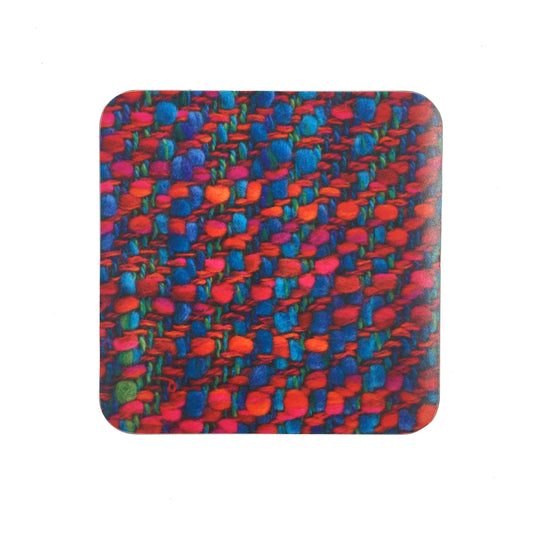 A square coaster with a photograph of the Bernat Klein fabric "Aurora". The fabric is woven in red, green, and blue.