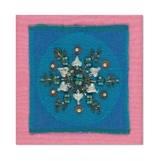 A square Christmas card with a photograph of a Christmas card with a snowflake design in beads and sequins on a blue-green fabric with a shocking pink fabric border.