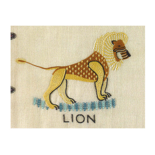 A horizontal rectangular greetings card with a photograph of an embroidered lion. The lion is embroidered in yellows and browns against a plain cream fabric background. Underneath the lion is the word "lion" embroidered in black.