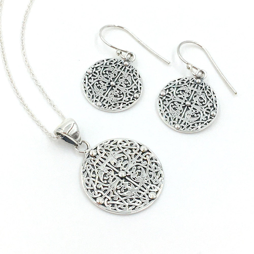 A pair of round drop earrings and a pendant, with a four way symmetrical design of four beasts, intertwined with vegetation, against a plain white background.