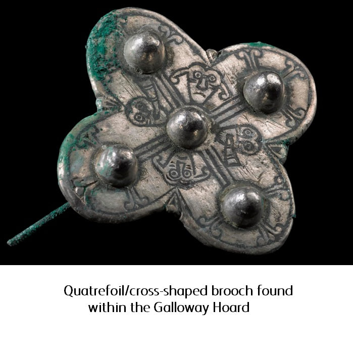 A silver brooch found in the Galloway hoard. A clover shaped brooch with a symmetrical design with faces engraved.