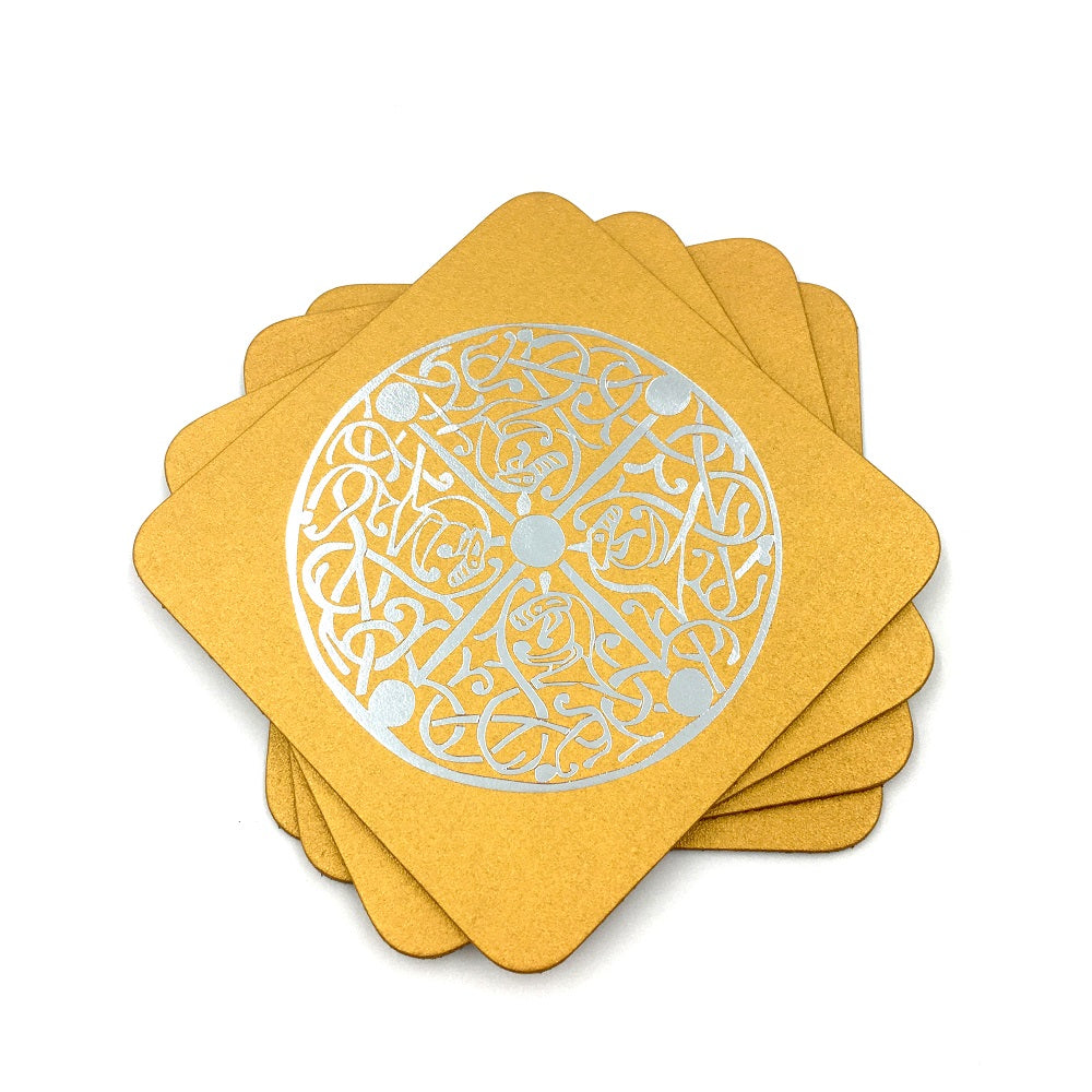Square gold imitation leather coasters with a silver design of a brooch from the Galloway hoard.