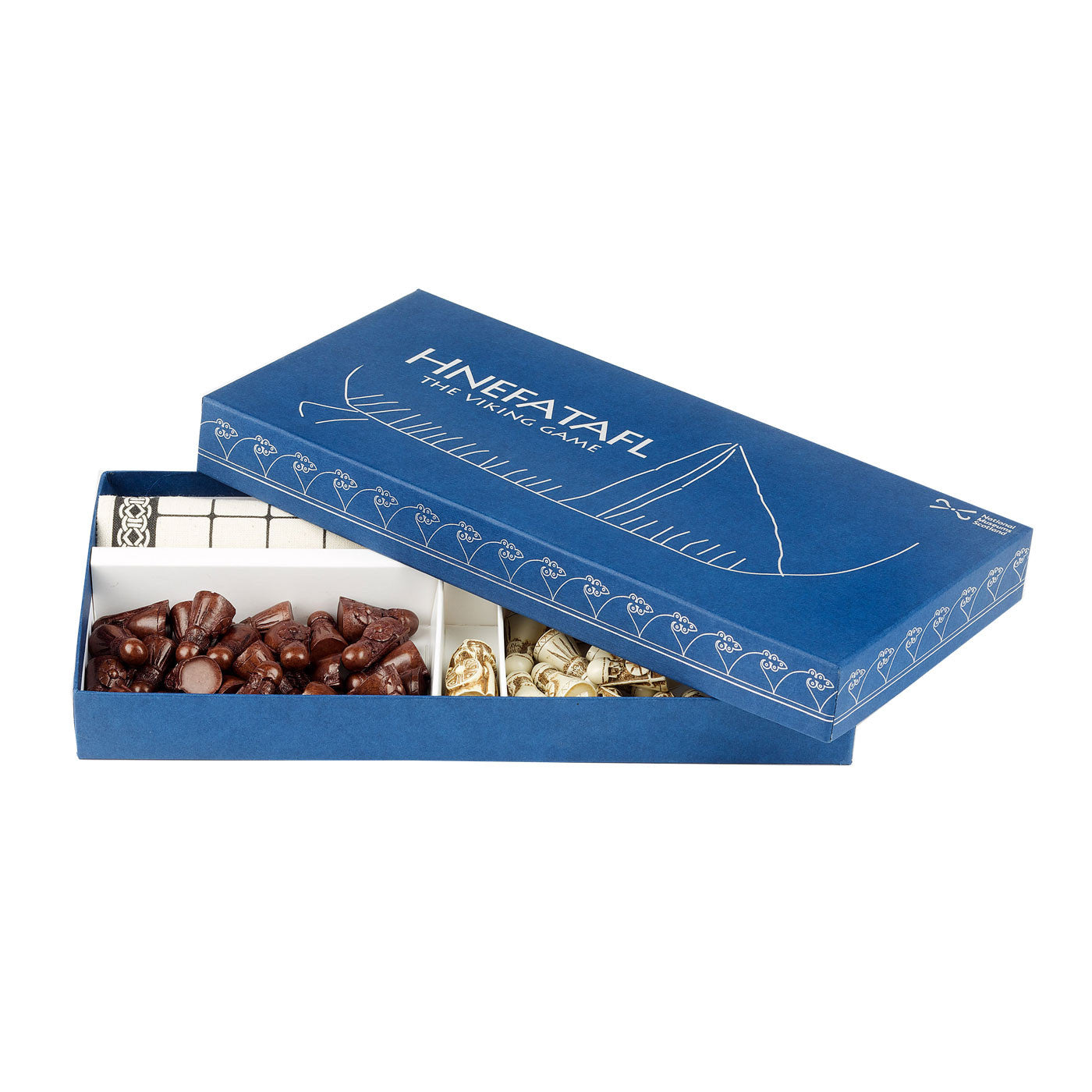 A navy blue box with the word "Hnefetafl" and an old carving of a viking long ship embossed in metallic silver, the National Museums Scotland logo is also embossed in the top right corner and a Norse inspired repeating around the edge. The lid is open slightly showing black and white Viking warrior pieces and a cloth game mat inside.